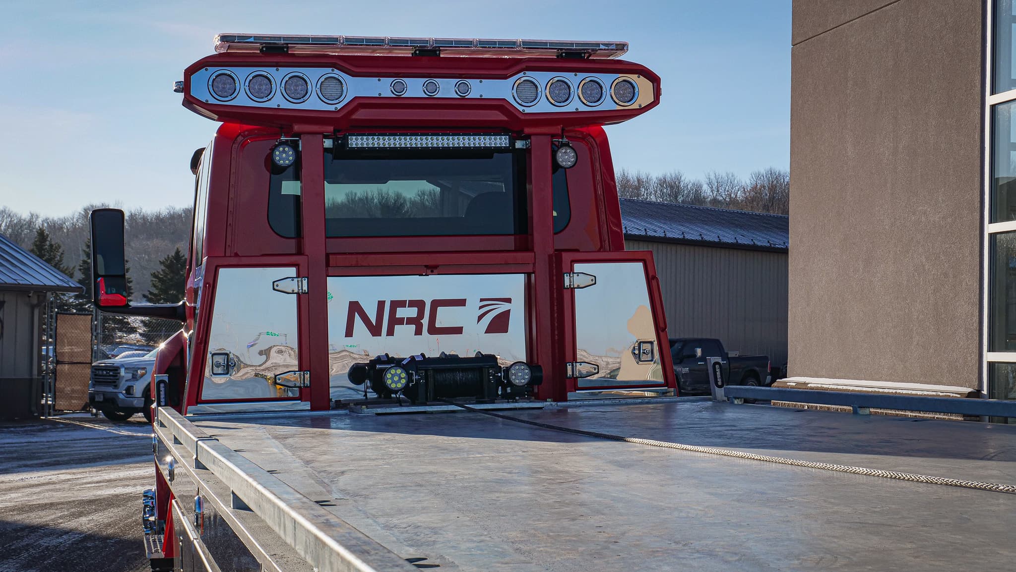 Red NRC tow truck viewed from the flatbed: NRC branding, work lighting, and winch behind the cab